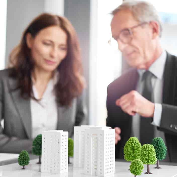 Man and woman sitting down in front of building model